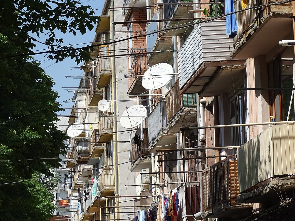Un bloque soviético en Gori, Georgia, con varias antenas parabólicas blancas en los balcones, todas hacia el mismo lado