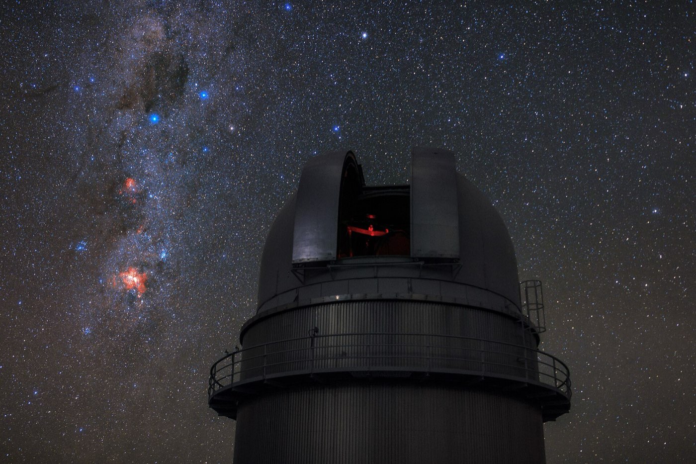 Una cúpula de telescopio en La Silla, Chile, bajo un cielo estrellado, con la Cruz del Sur en la Vía Láctea a su izquierda