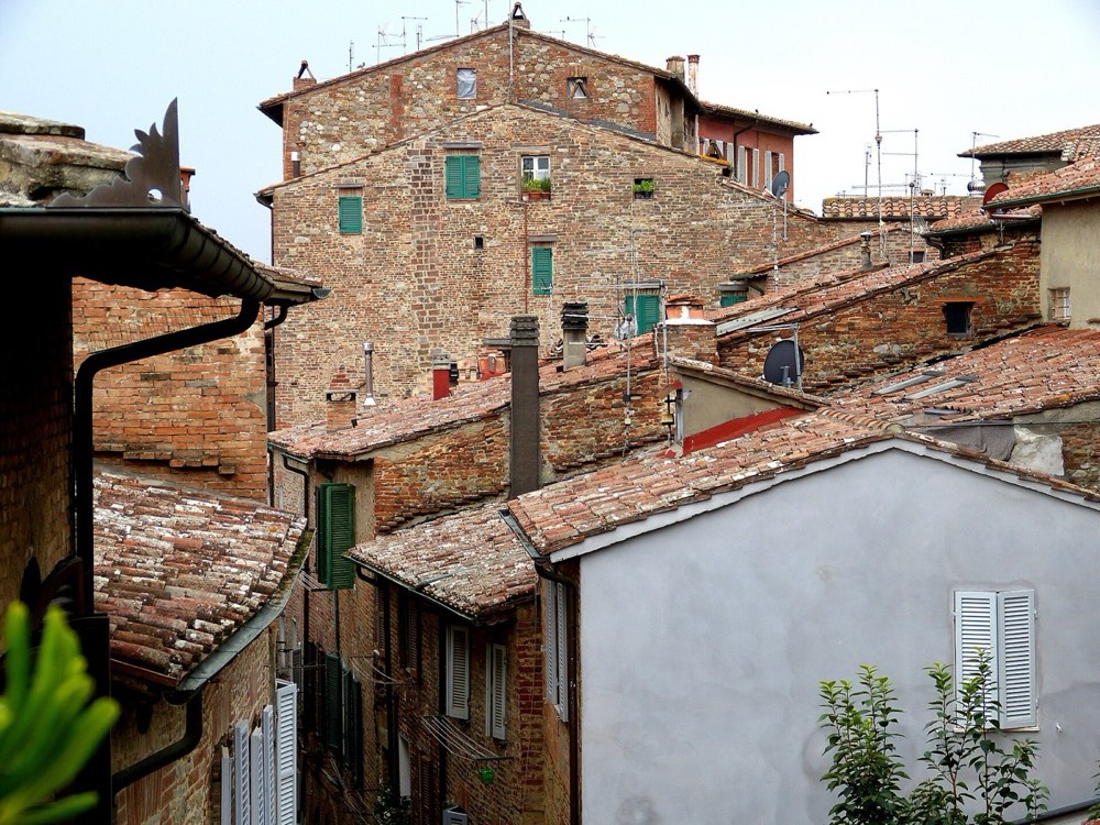 Low-pitched terracotta barrel-tiled roofs and green louvred shutters in an Italian hill town