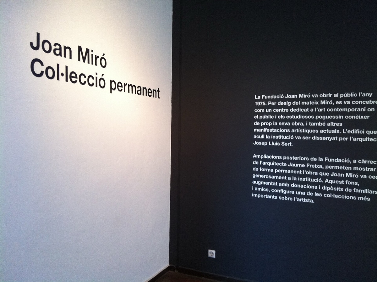 Museum wall lettering reading Joan Miró Col·lecció permanent next to a dark panel of Catalan text