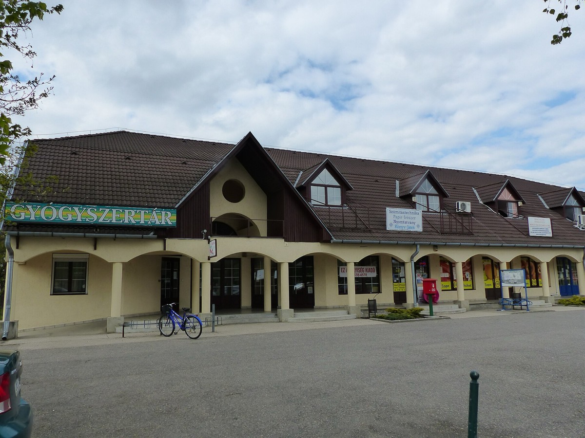 A long low shop building with a wide green sign reading GYÓGYSZERTÁR above the arcade