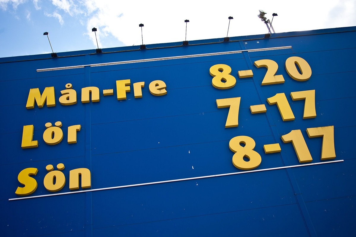 Large yellow letters on a blue shop wall reading Mån-Fre 8-20, Lör 7-17 and Sön 8-17