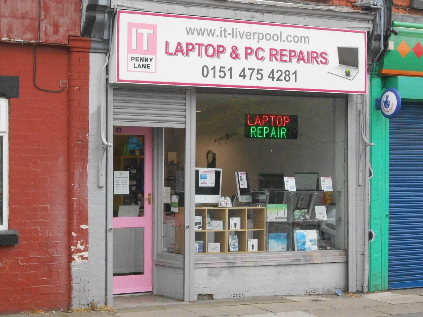 Rosa-weißes Ladenschild mit www.it-liverpool.com, LAPTOP & PC REPAIRS und 0151 475 4281 über einem Schaufenster