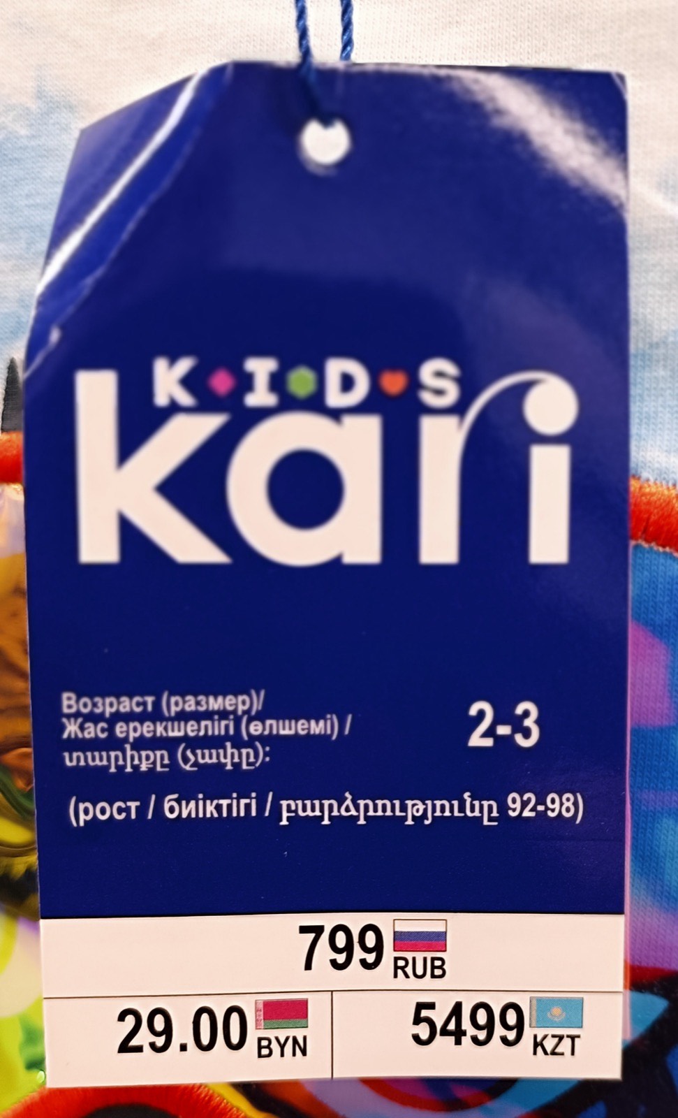 Preisetikett für Kleidung mit den Preisen 799 RUB, 29.00 BYN und 5499 KZT, jeweils neben einer kleinen Landesflagge